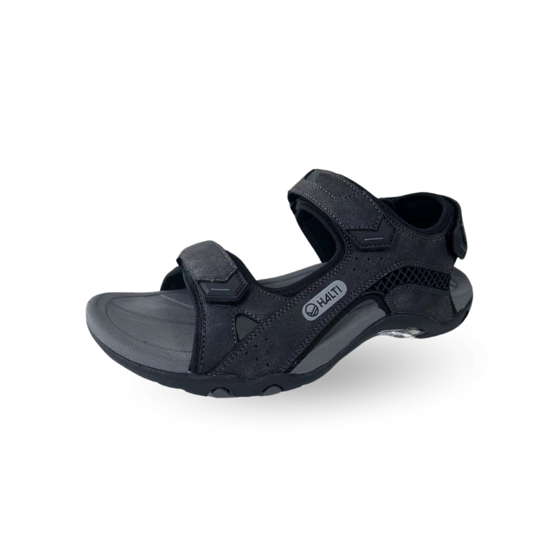 Mustassa Halti Route Outdoor -sandaalissa on ergonomisesti muotoiltu pohjallinen ja teksturoitu pohja valkoista taustaa vasten.