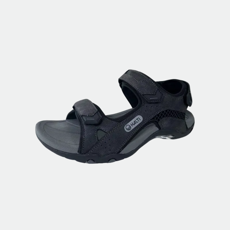 Mustassa Halti Route Outdoor -sandaalissa on ergonomisesti muotoiltu pohjallinen ja teksturoitu pohja valkoista taustaa vasten.