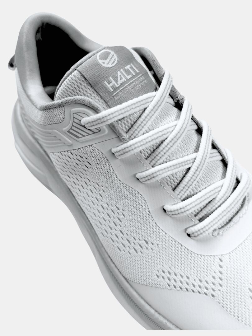 Halti Tempo 3 Lenkkari Miesten on valkoinen urheilukenkä, jossa on verkkomateriaalia, Comfort+ -sisäpohja ja harmaa logo kielellä.