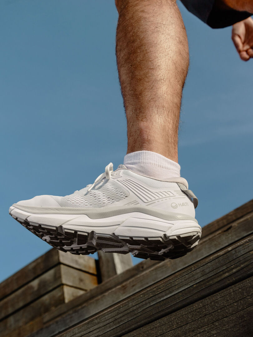 Mies Haltin Tempo 3 Lenkkari Miesten seisoo puun päällä – ihanteellinen mukavuus koville alustoille, sininen taivas yllä.