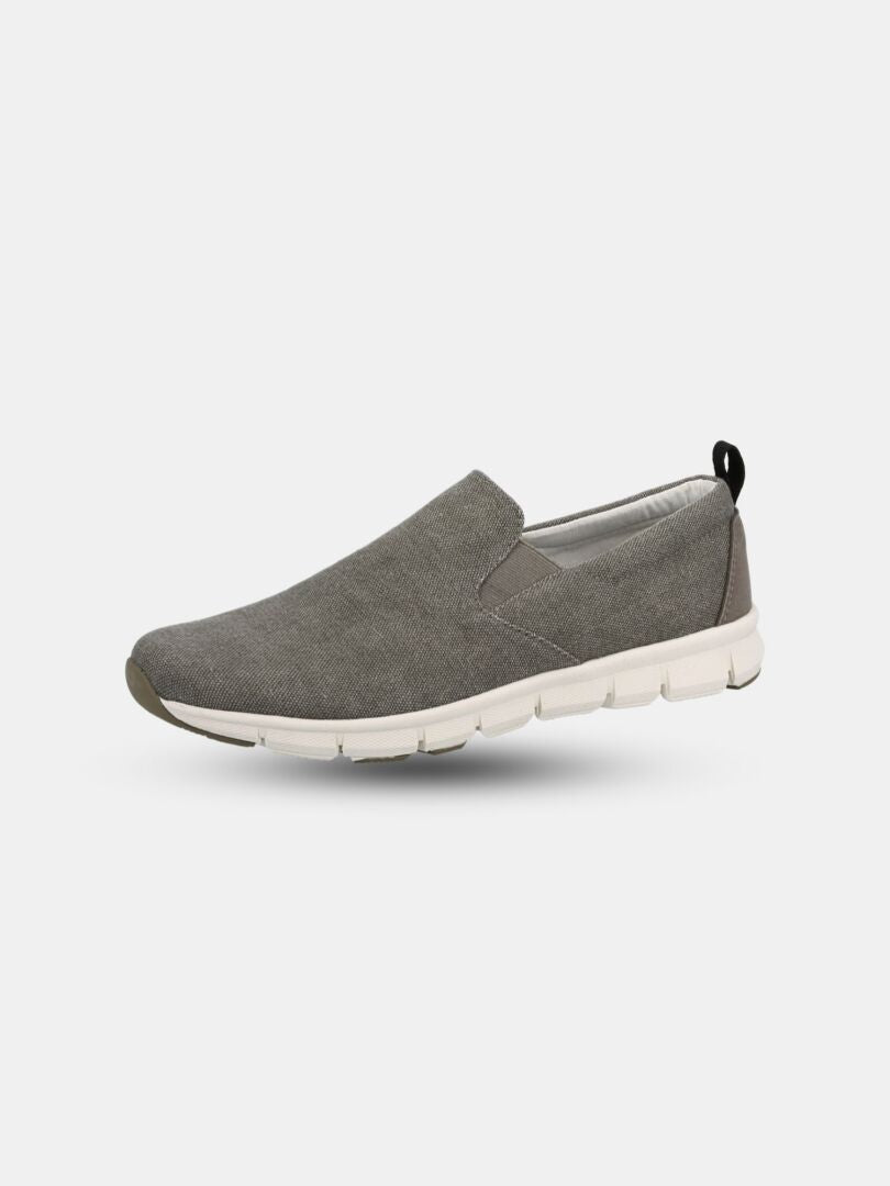 Halti Lente Canvas Vapaa-ajan Kenkä Miesten: harmaa slip-on, jossa valkoinen pohja, musta vetoliuska ja hengittävä rakenne.