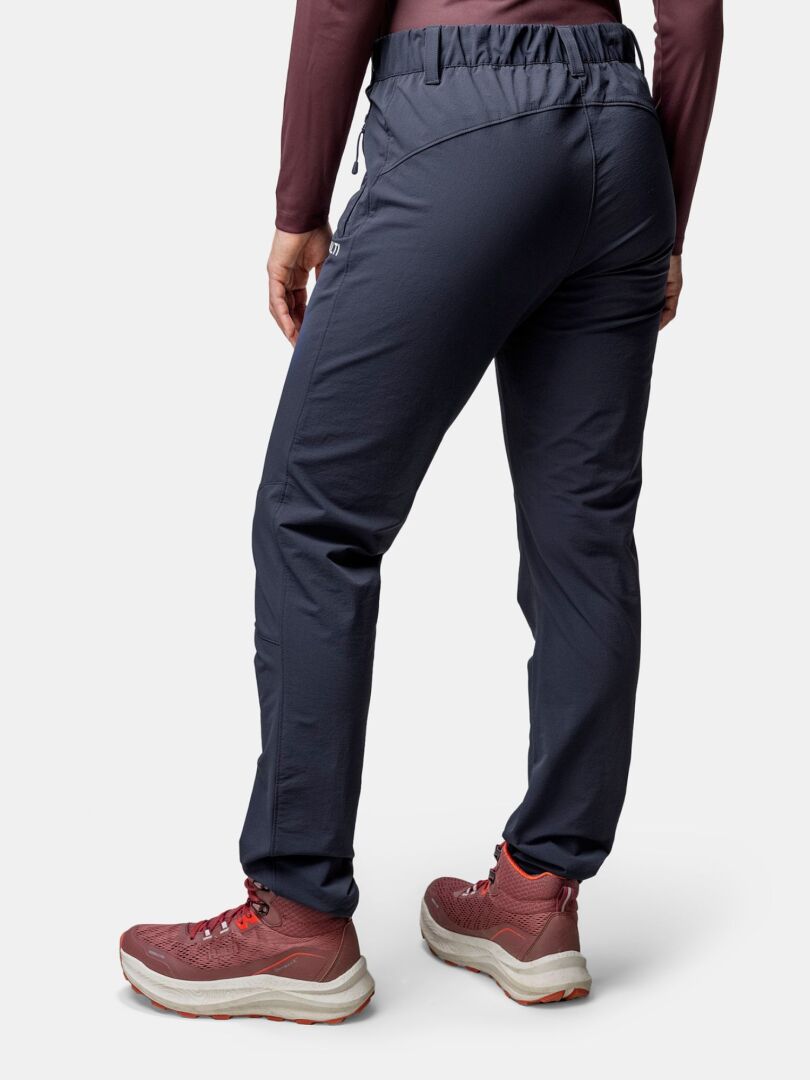 Henkilö tummissa lenkkihousuissa, ruskeankeltaisessa pitkähihaisessa ja Halti Rapid DX Mid Ulkoilukenkä Naisten, kuvattuna takaa.