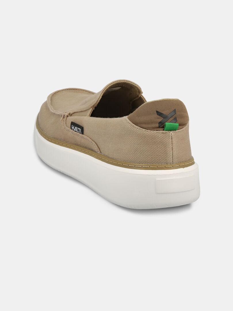 Halti Lido Canvas Kenkä Miesten on ruskehtava slip-on, jossa on valkoinen pohja ja Halti-logomerkki takana vasemmalla.