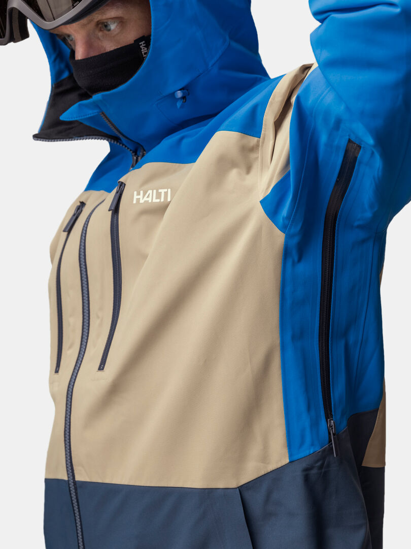 Henkilö sininen ja beige Halti Rizle 3L DX Laskettelutakki Unisex säätöhuppu, DrymaxX Nano yksityiskohdat näkyvissä.