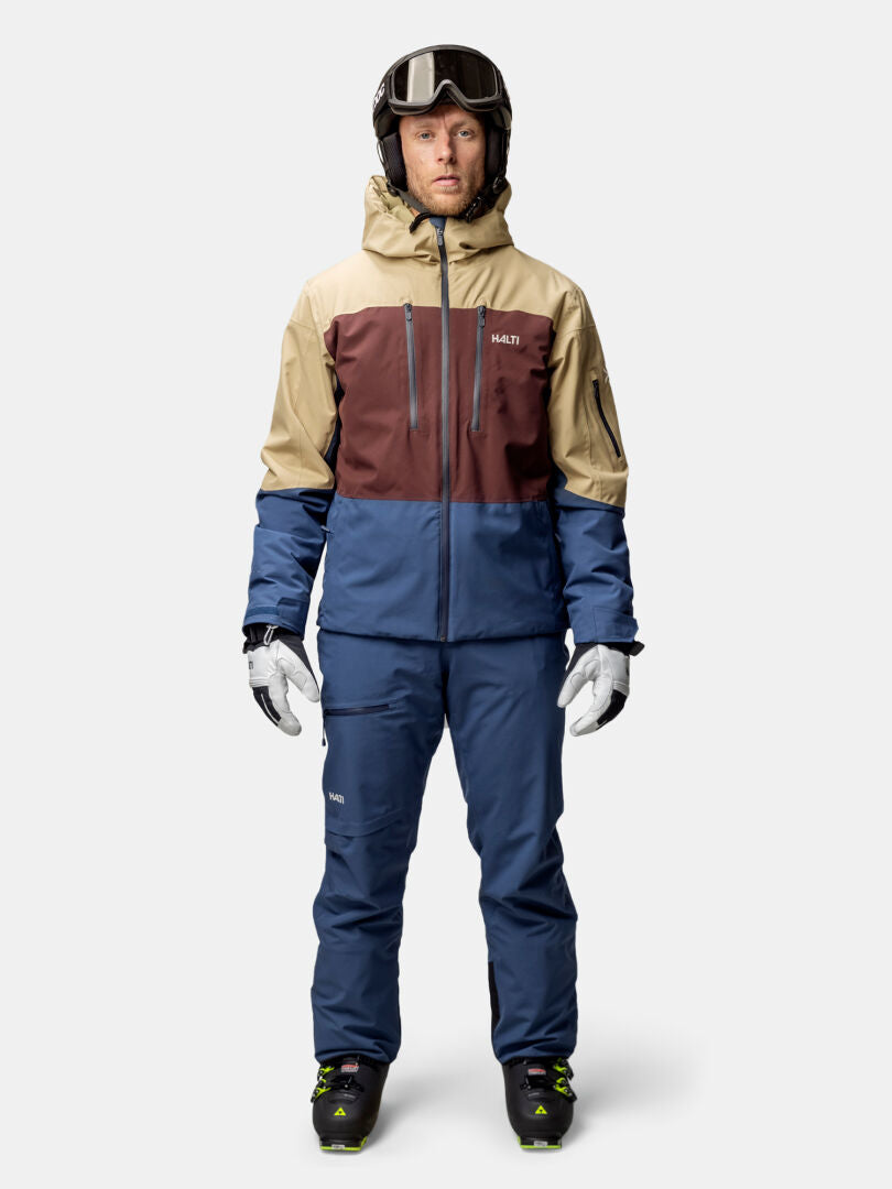 Henkilö Halti Melvik DX Laskettelutakki Miesten, siniset housut, hanskat, kypärä ja hiihtokengät.
