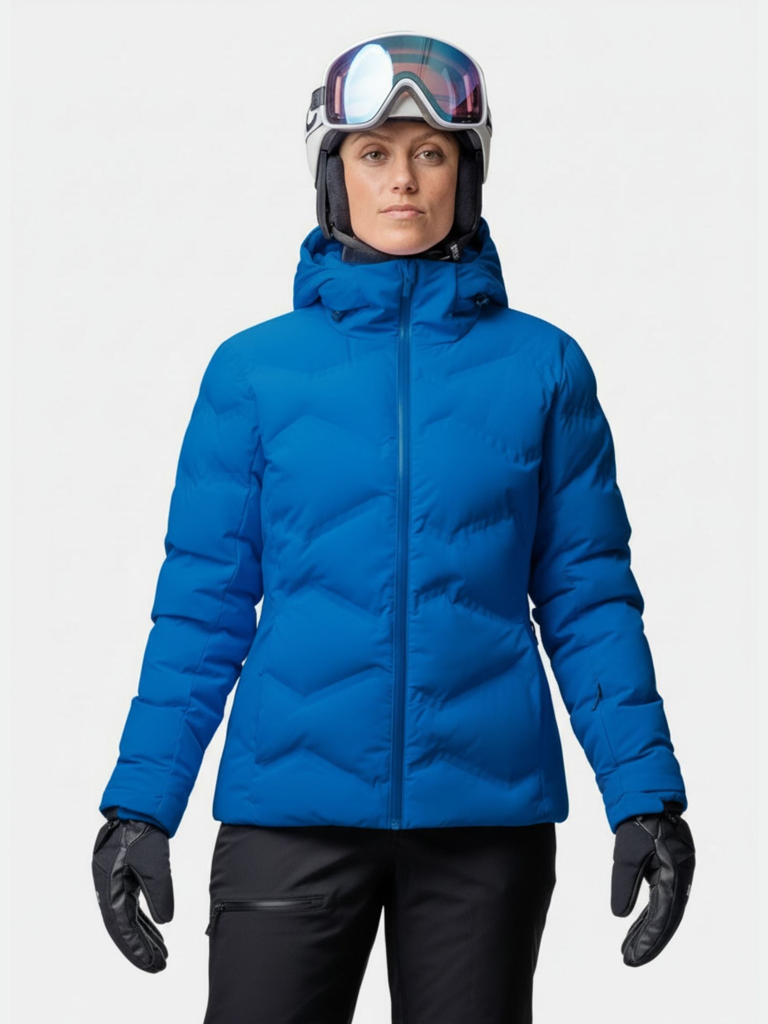 Siniseen Halti Nordic Arcty II Laskettelutakki Naisten, mustiin hanskoihin, kypärään ja suojalaseihin pukeutunut henkilö seisoo tavallista taustaa vasten.