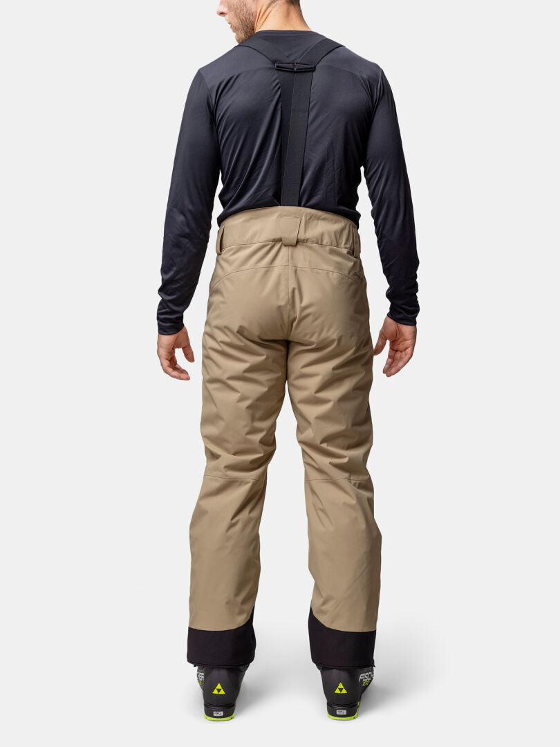 Mies katsoo poispäin yllään Halti Carvey II DX miesten lasketteluhousut vedenpitävä DrymaxX ja mustat henkselit.