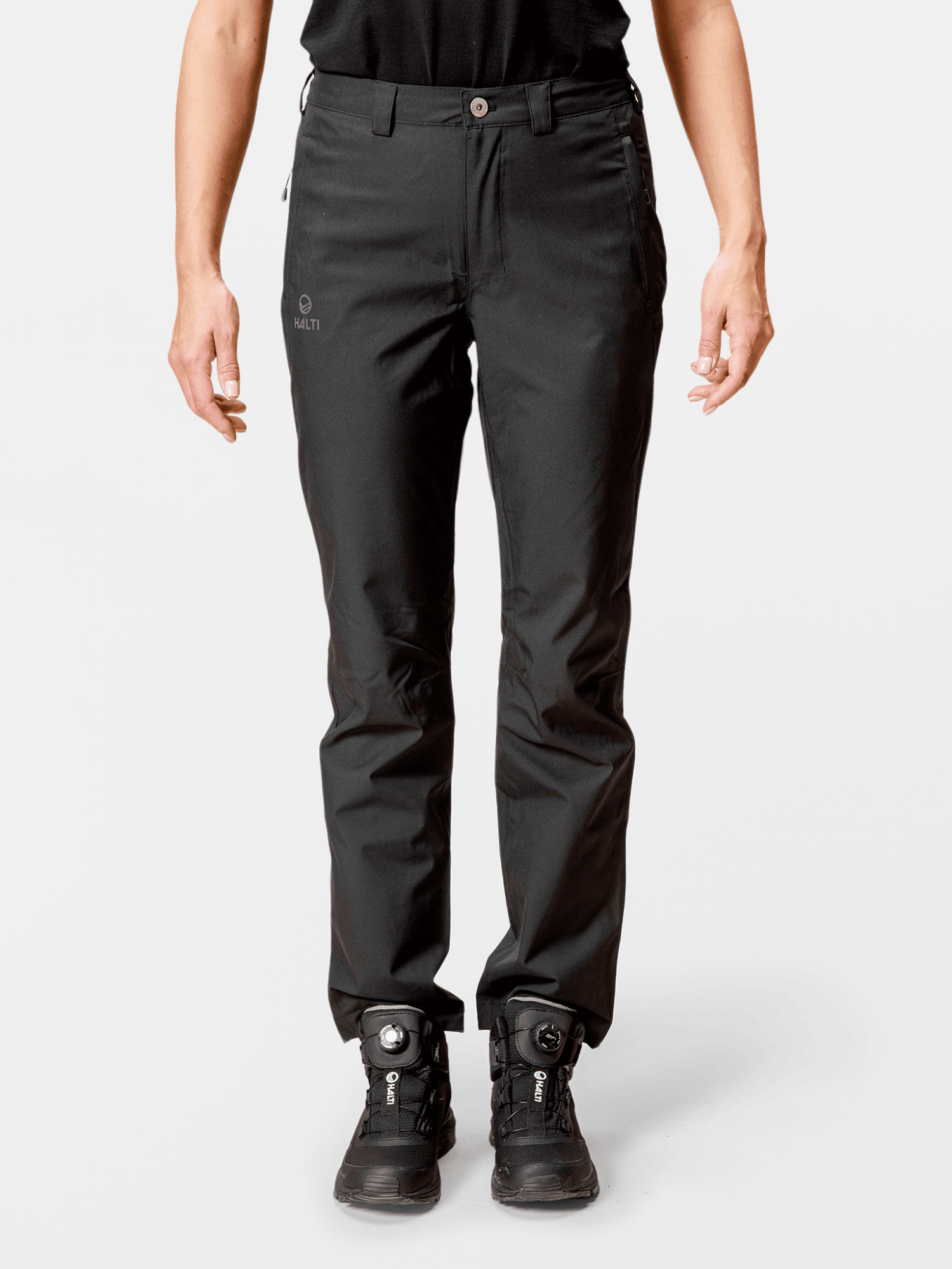 Henkilö, jolla on yllään Halti Leisti Naisten Recy Long DrymaxX Kuorihousut, seisoo vaaleaa taustaa vasten kädet rentoina.