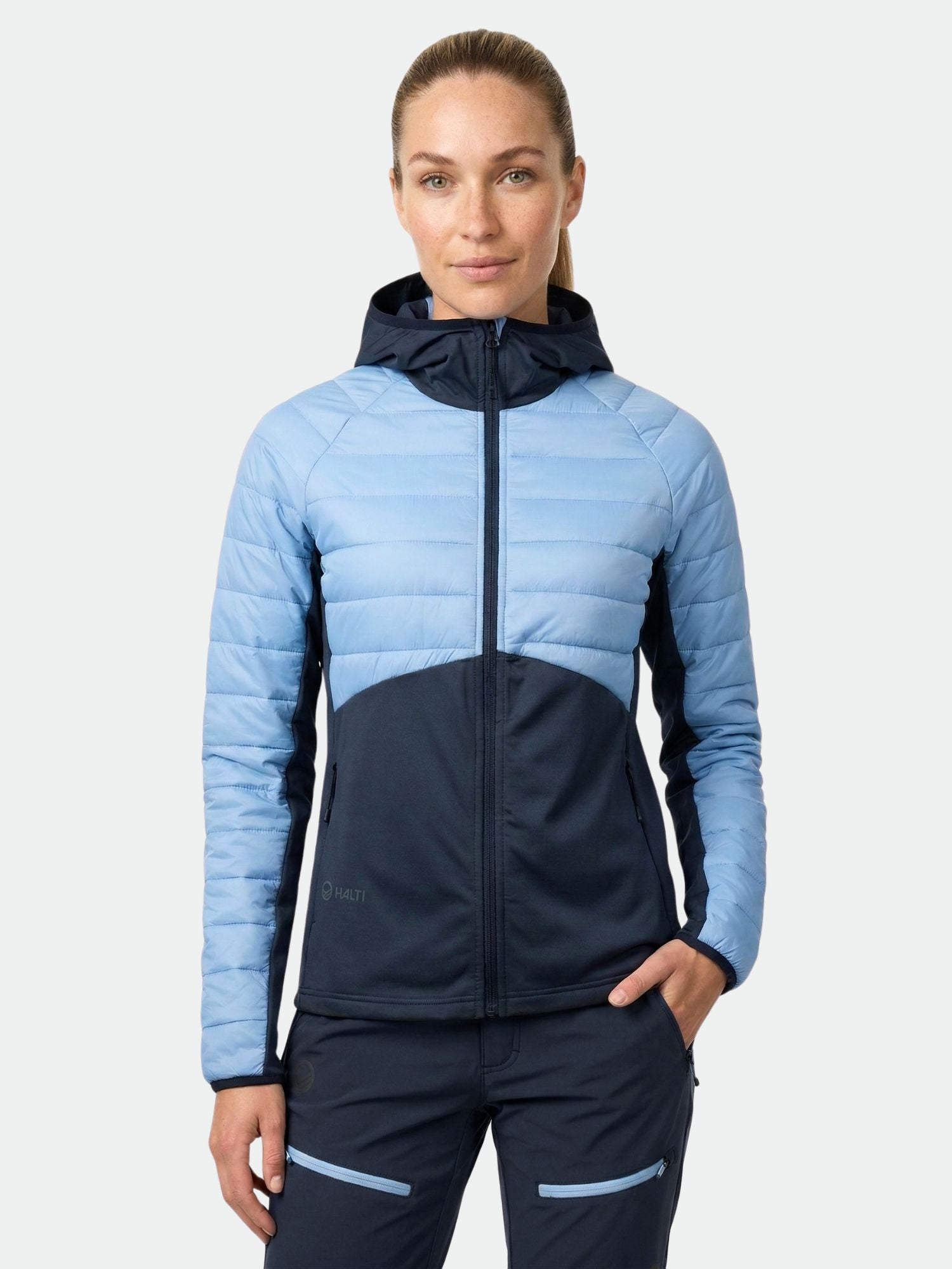 Halti Veidnes Naisten Välitakki -nainen, kädet taskuissa, seisoo tavallista taustaa vasten.