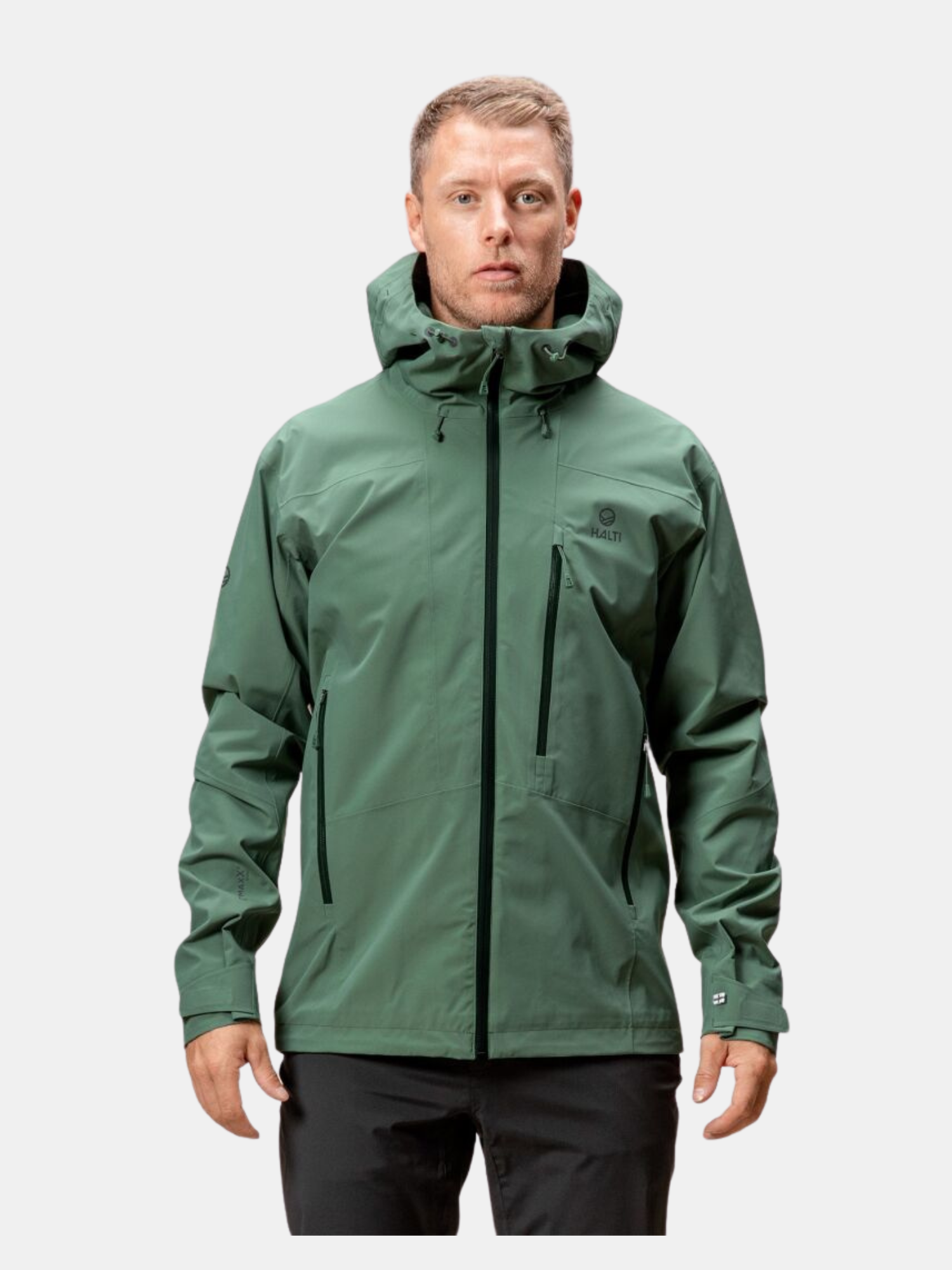 Miehellä on yllään vihreä Halti Juonto DrymaxX Kuoritakki Miesten mustalla vetoketjulla eteenpäin, valkoisella pohjalla.
