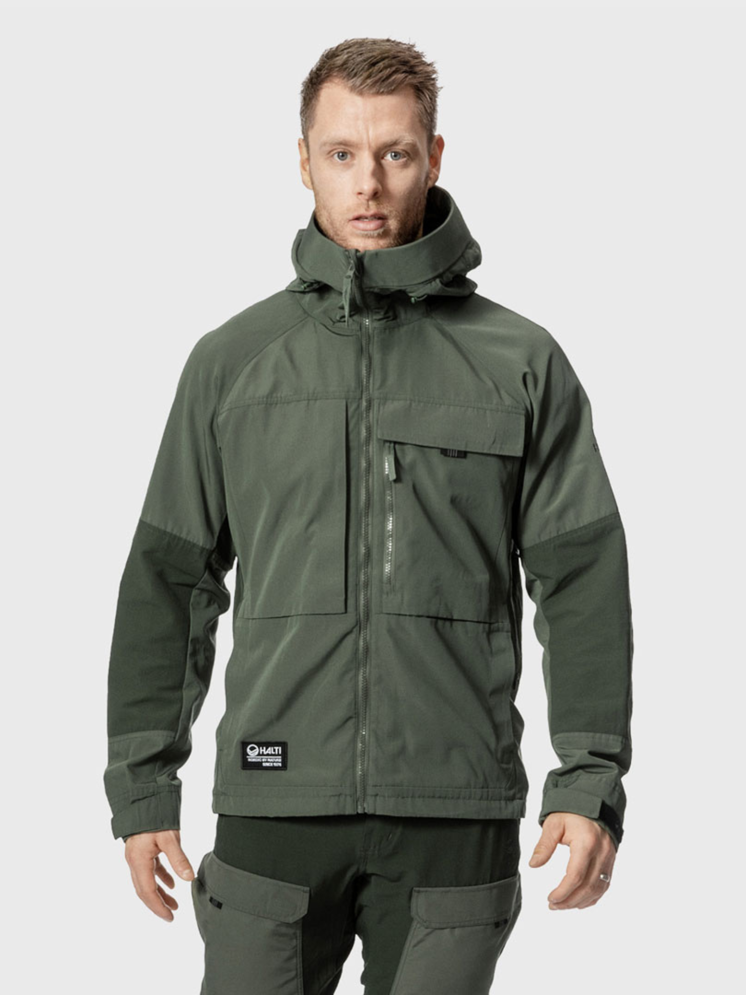 Mies Halti Hiker Miesten Ventilated Retkeilytakissa seisoo kasvot eteenpäin vaaleaa taustaa vasten.