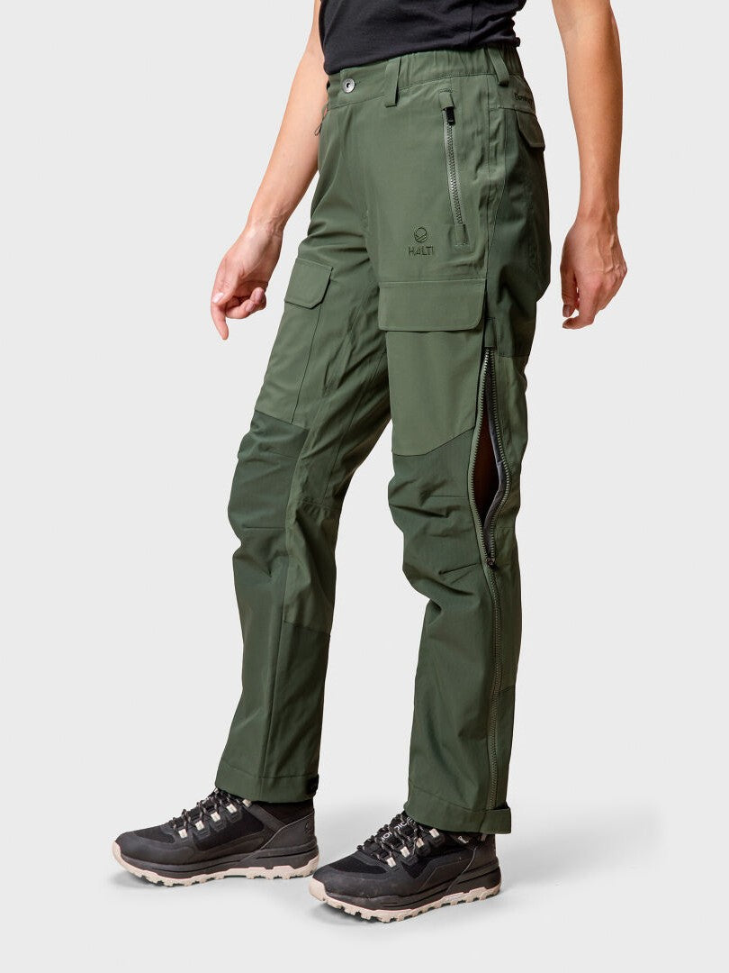 Henkilöllä on yllään tummanvihreä Halti Hiker DrymaxX 3L Ventilated Retkeilyhousut Naisten, mustat vaelluskengät ja musta paita.