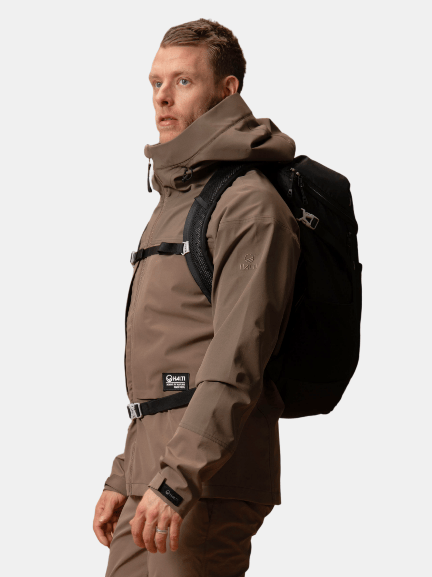 Halti Hiker II DrymaxX Kuoritakki Miesten ja musta repussa oleva henkilö seisoo vasemmalla valmiina vaellukselle.