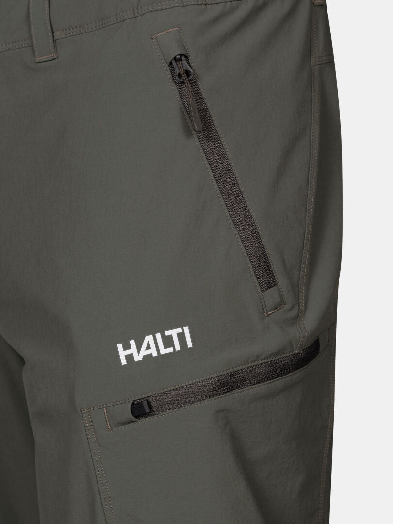 Lähikuva Halti Pallas Evo X-stretch Housut Miesten tummanvihreästä stretch-materiaalista ja Halti-logosta reidessä.