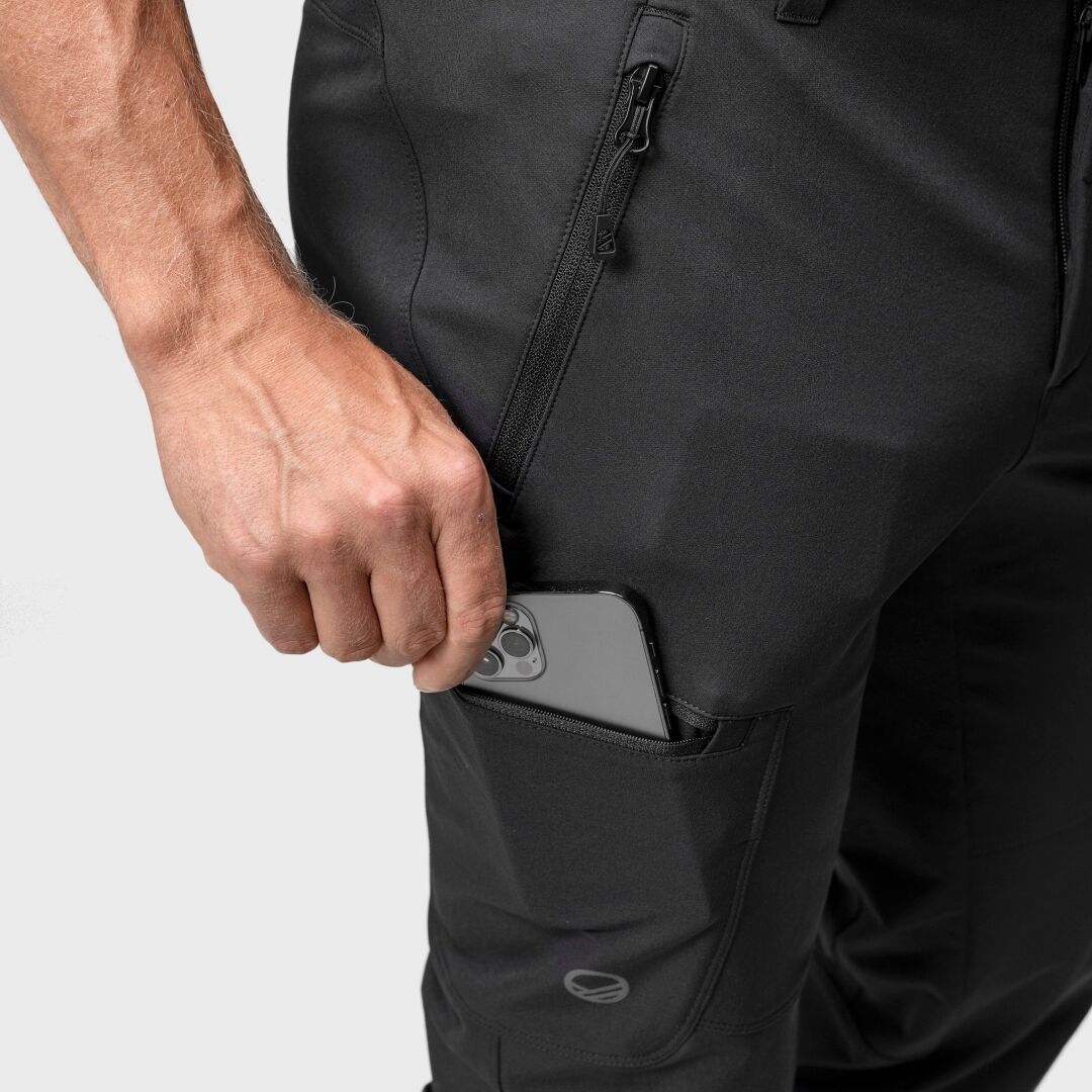 Henkilö sujauttaa älypuhelimen Halti Pallas Evo Brushed X-stretch Ulkoiluhousut Miesten vetoketjulliseen reisitaskuun.