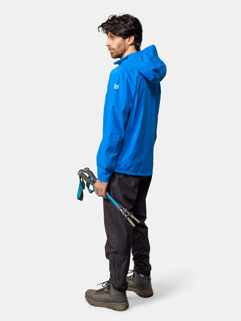 Mies Halti Pisarat 2,5L DX Kuoritakki Miesten ja mustat housut pitelee vaellussauvoja ja katsoo sivulle.