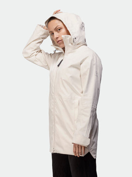 Henkilö, jolla on yllään Halti Kallas DX Parkatakki Naisten takki, seisoo ja katsoo kameraan toinen käsi hupun päällä.