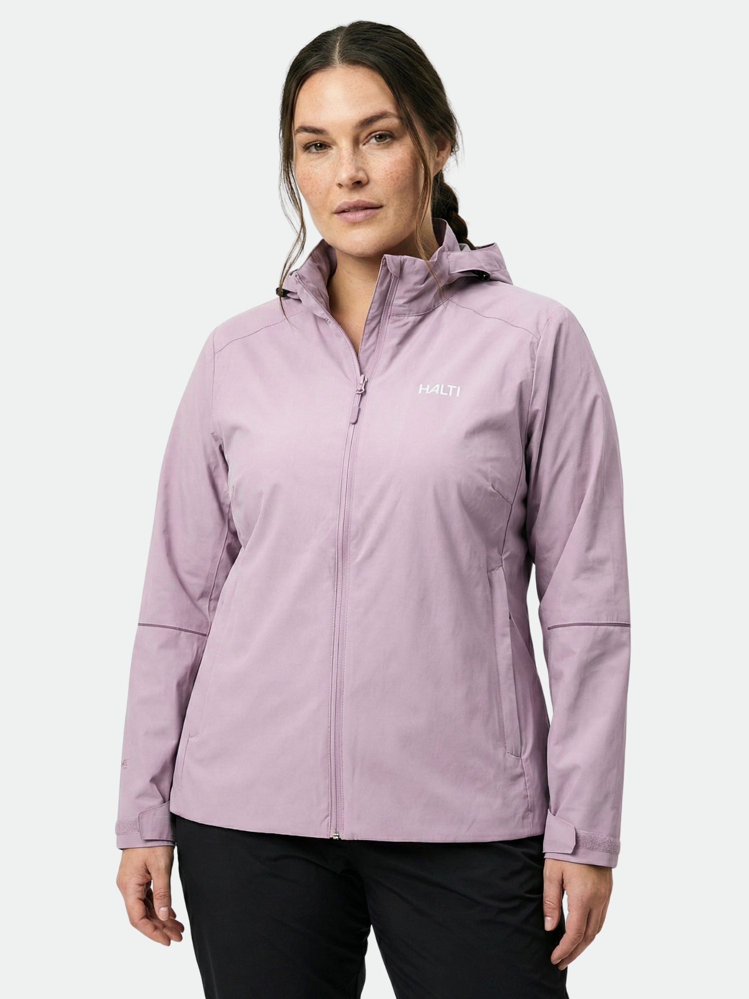 Nainen, jolla on Halti Staala DX Kuoritakki Naisten Plus (vaaleanvioletti) ja mustat housut, seisoo kasvot menosuuntaan.