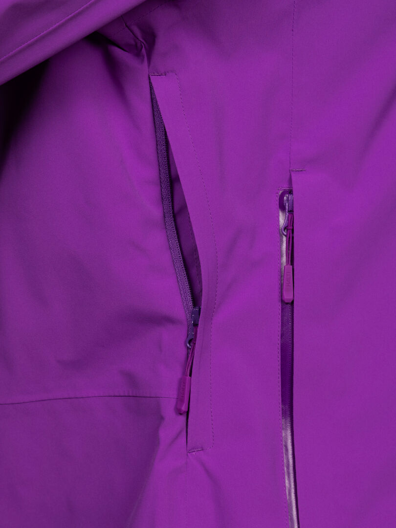 Lähikuva Halti Staala DX Naisten kuoritakista, jossa on kaksi vetoketjullista taskua ja niihin sopivat violetit vetoketjun vetimet.