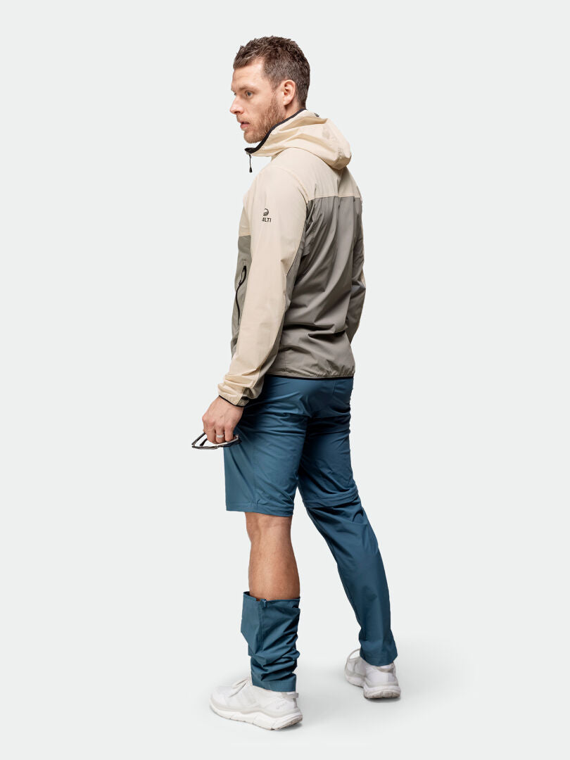 Miehellä profiilissa yllään Halti Pallas Cool X-stretch Takki Miesten, beigenharmaa, sinisissä shortseissa – ihanteelliset kesäaktiviteetteihin.