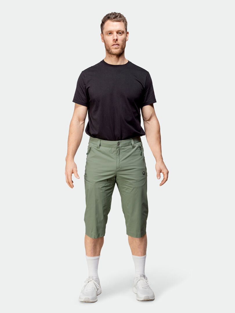 Mies katsoo eteenpäin yllään musta t-paita, Halti Pallas Cool X-stretch -caprit, valkoiset sukat ja valkoiset lenkkarit.