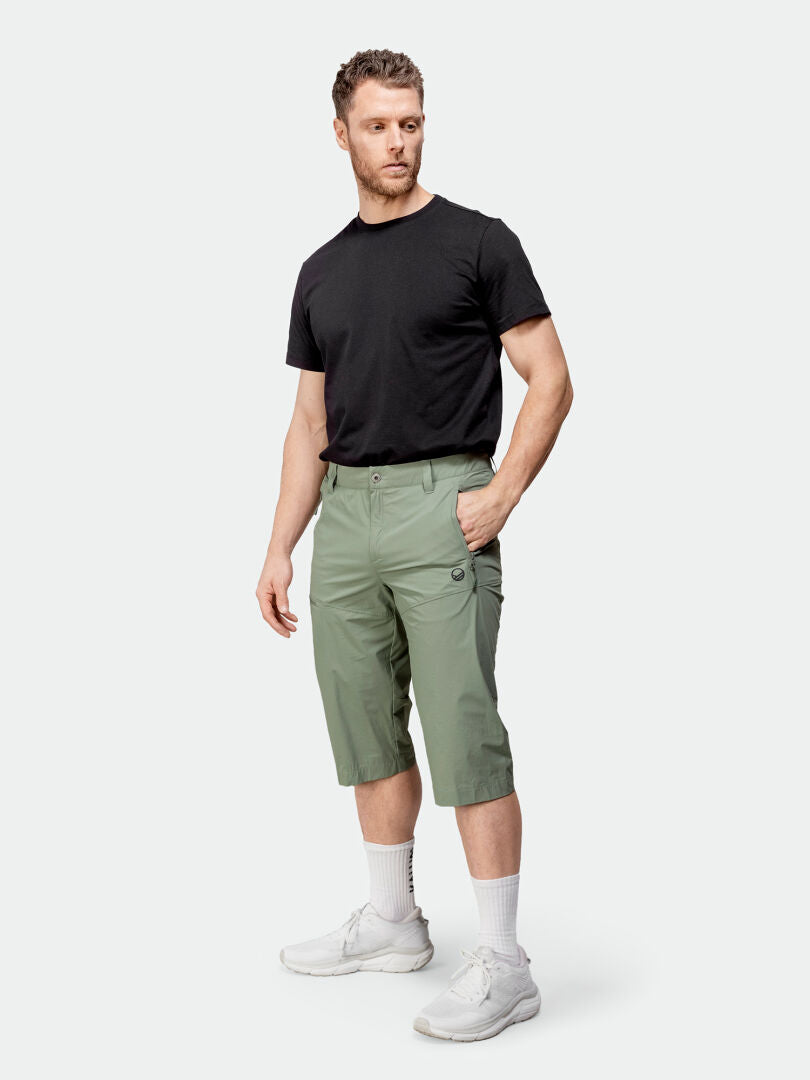 Miehellä on yllään Halti Pallas Cool X-stretch Miesten Caprit, musta t-paita, valkoiset sukat ja lenkkarit.