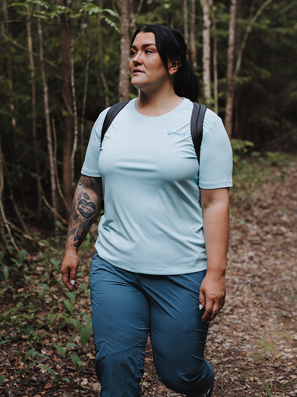 Halti Pallas Cool X-stretch Caprit Plus -takkiin pukeutunut henkilö vaeltaa mustassa repussa nauttien viileästä ja joustavasta mukavuudesta.