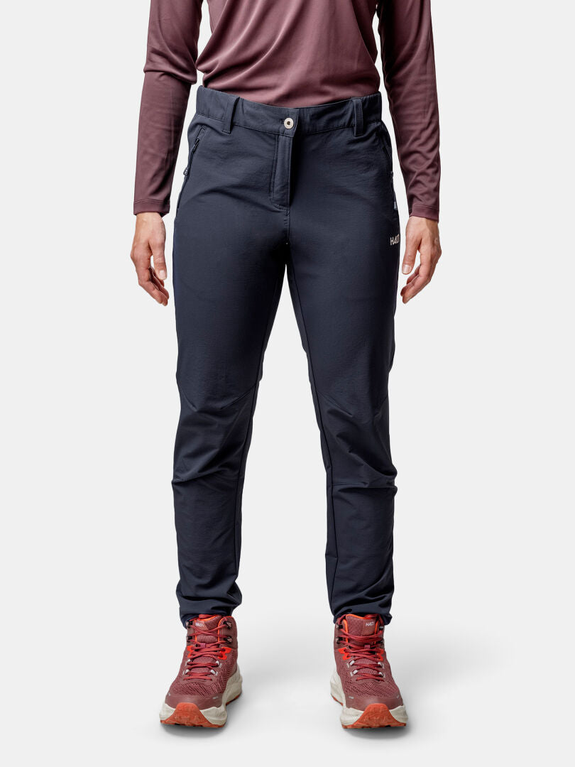 Henkilöllä on yllään Halti Finholma X-stretch Housut Naisten, ruskeankeltainen pitkähihainen paita ja punaiset polkukengät.