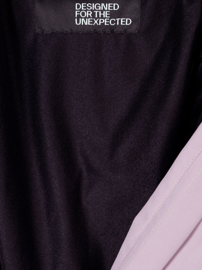 Halti Valaja DX Parkatakki Naisten sisällä olevassa mustassa kangaslapussa lukee DESIGNED FOR THE UNEXPECTED vaalean violetilla vuorauksella.