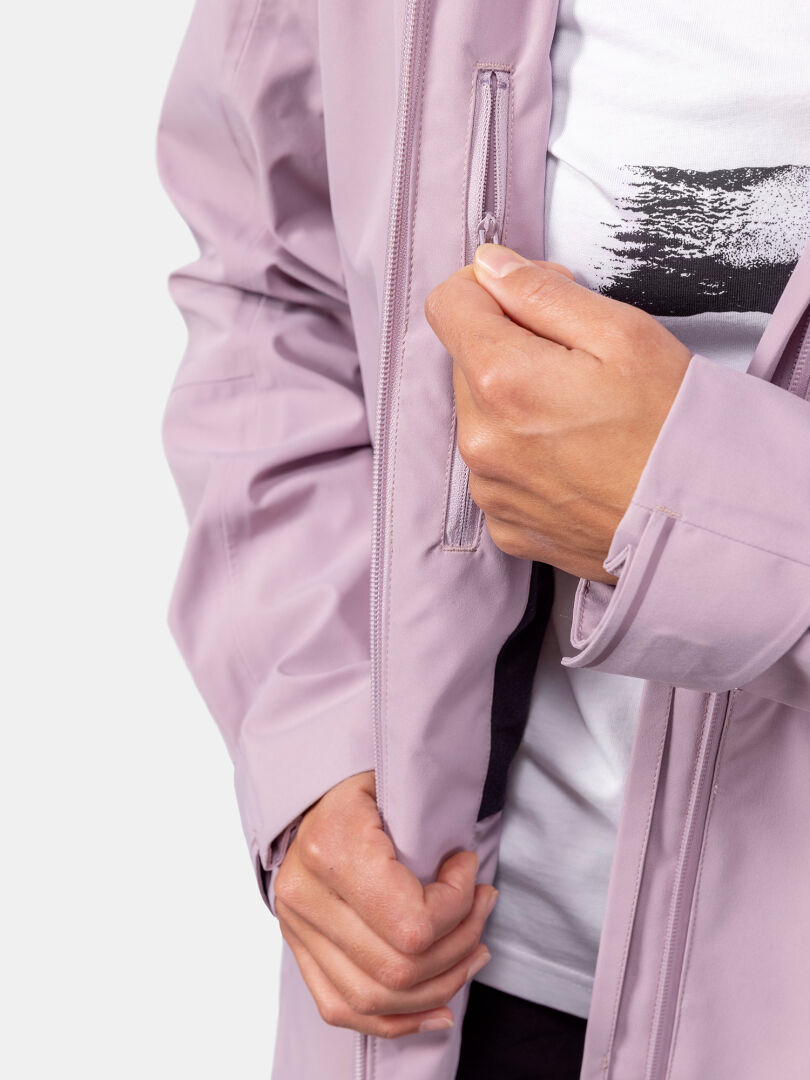 Halti Valaja DX Parkatakki Naisten henkilö avaa rintataskun, jolloin sen alta paljastuu osa valkoisesta painetusta paidasta.