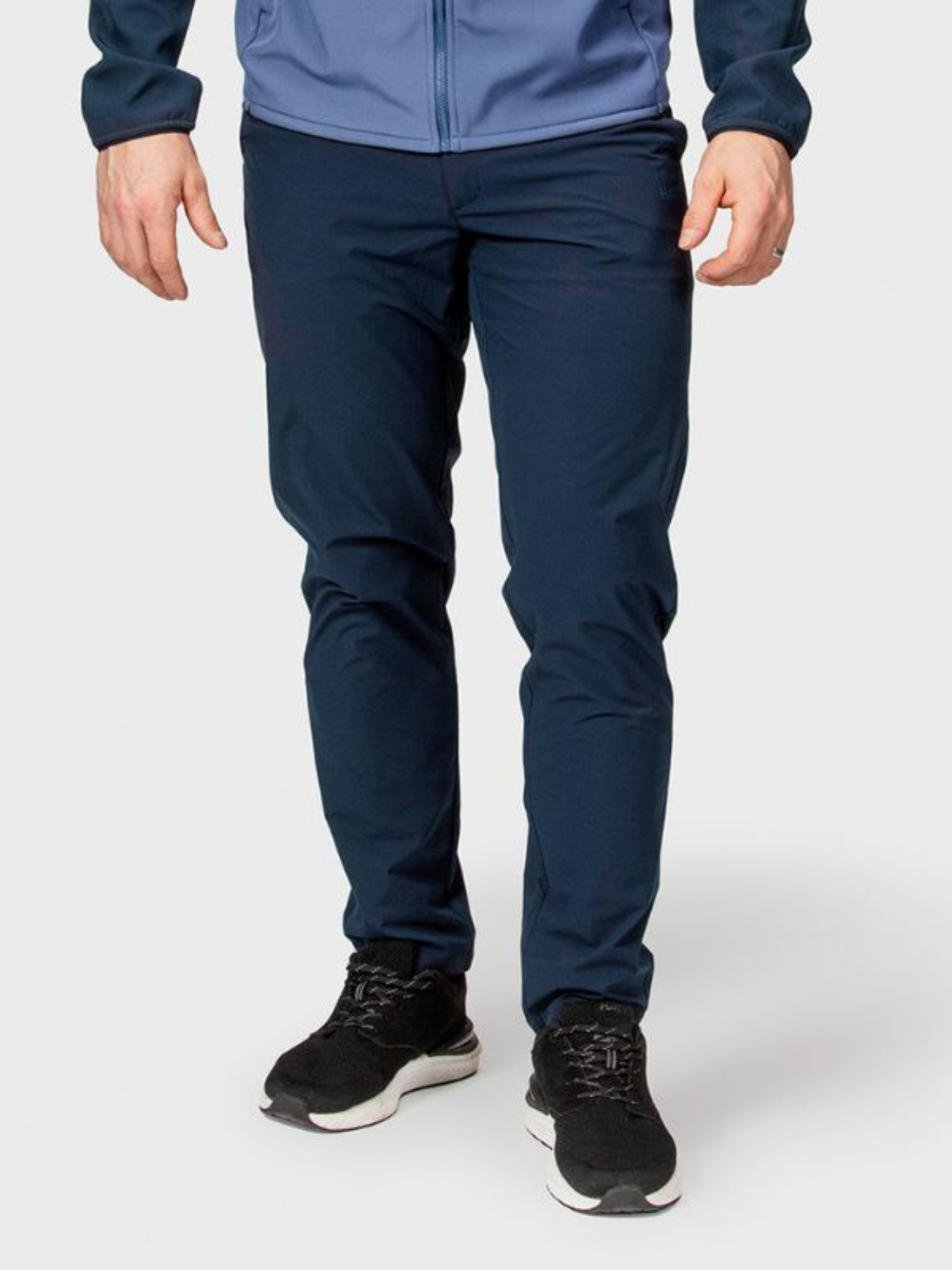 Henkilö Halti Drive Miesten X-stretch -chinot-takissa, jossa on sininen takki ja mustat urheilukengät.