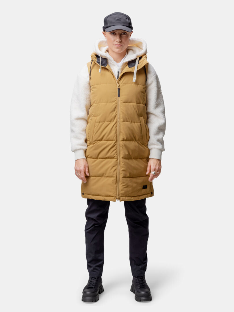 Henkilö, jolla on yllään ruskehtava Halti Penger Toppaliivi Naisten, valkoinen huppari, mustat housut, saappaat ja musta lippis, kasvot eteenpäin.