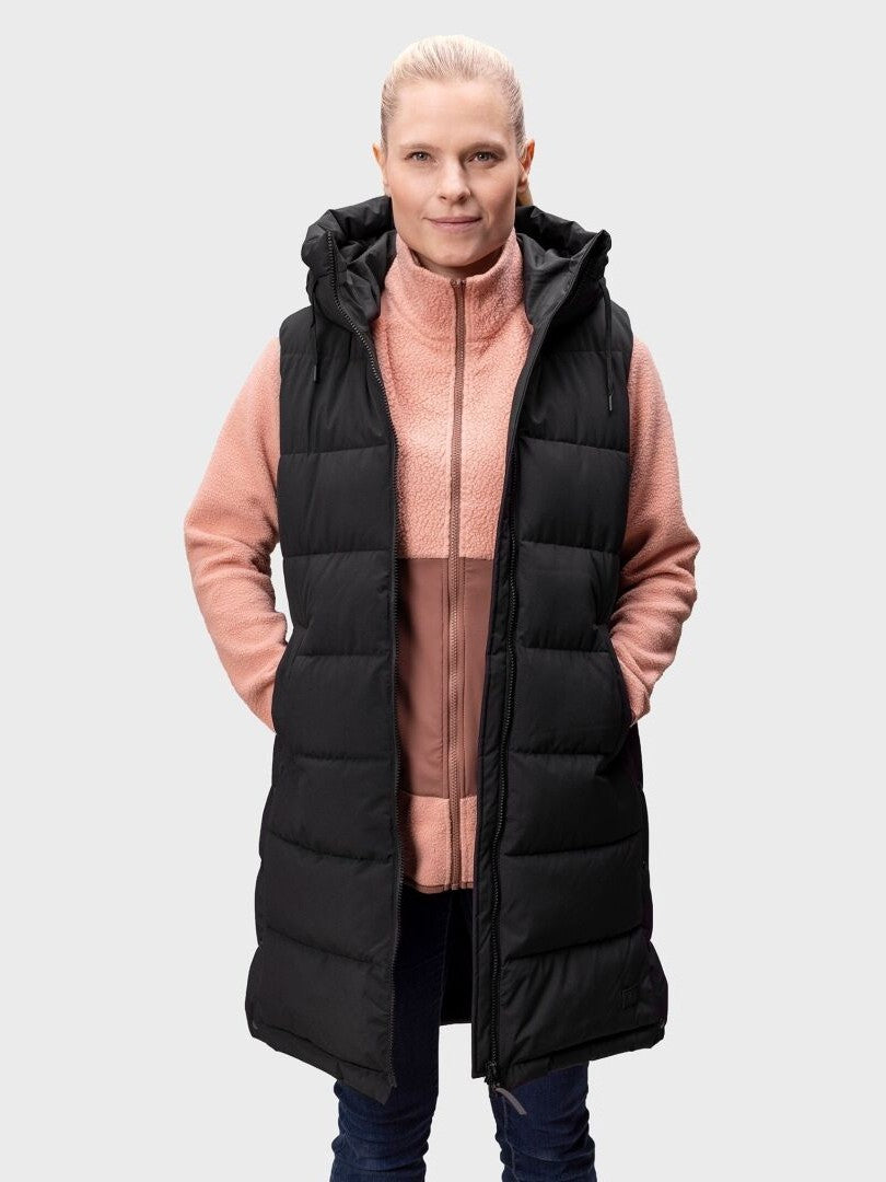 Henkilö, jolla on vaaleanpunainen vetoketjutakki ja Halti Penger Toppaliivi Naisten seisoo kameraan päin kädet liivien taskuissa.