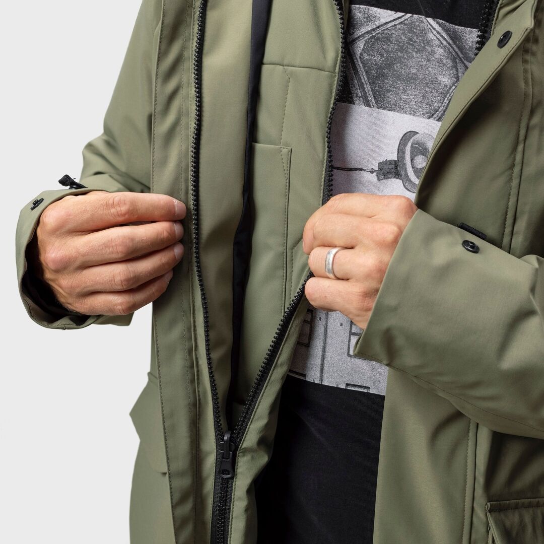 Mies Halti Synkas 3in1 DrymaxX -parkatakissa (kierrätetystä polyesteristä) avaa takin vetoketjun ja paljastaa mustan kamerapaidan.