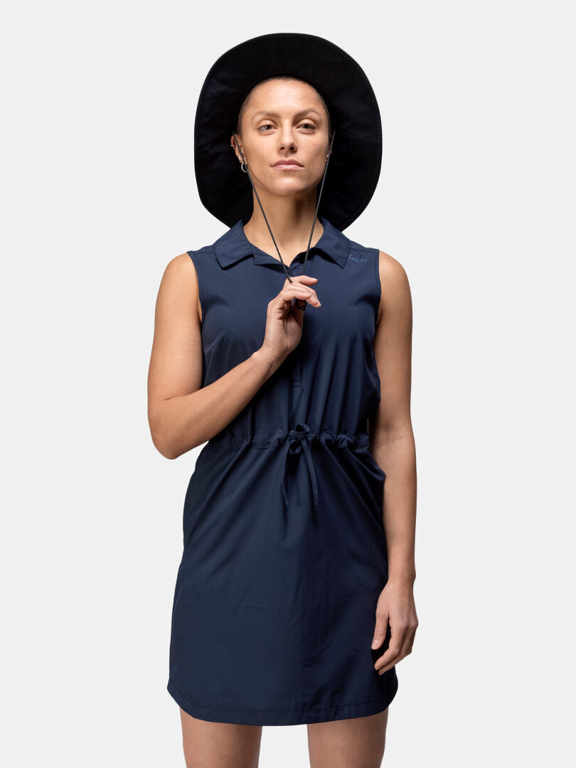 Nainen Halti Chipper X-stretch Mekko Naisten hatussa ja leveälierisessä hatussa seisoo vaalean taustan edessä.