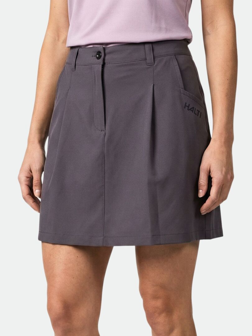 Henkilöllä on yllään Halti Drive X-stretch Shortsihame, polvipituinen tummanharmaa hame, jossa on sivutaskut, ja vaaleanvioletti toppi.