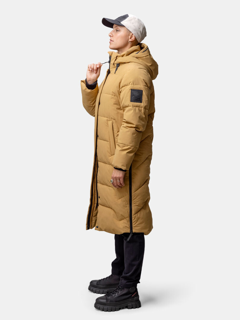 Ruskehtava Halti Brahe Puffer Pitkä Talvitakki Naisten seisoo sivuttain mustissa housuissa ja kengissä.