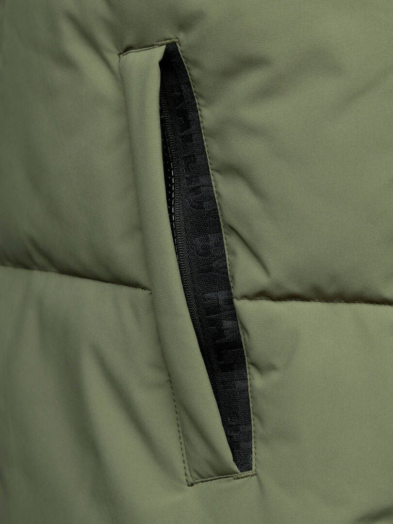 Lähikuva Halti Penger Classic Puffer Liivi Miesten vihreästä, mustalla vetoketjulla sivutaskussa, valmistettu kierrätetystä polyesteristä.