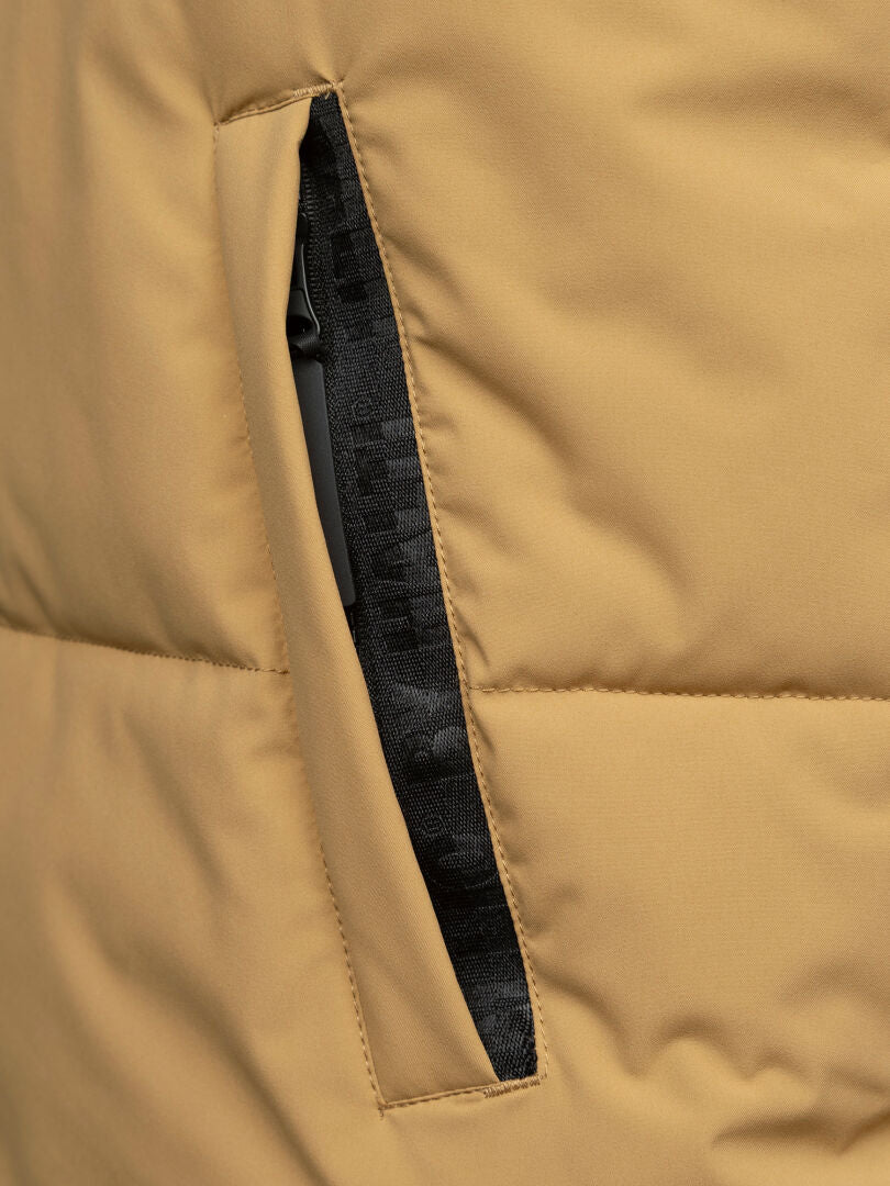 Lähikuva Halti Penger Classic Puffer Liivi Miesten puskurista, jossa on ruskea pehmuste, musta vetoketjutasku ja kierrätyspolyesterivuori.