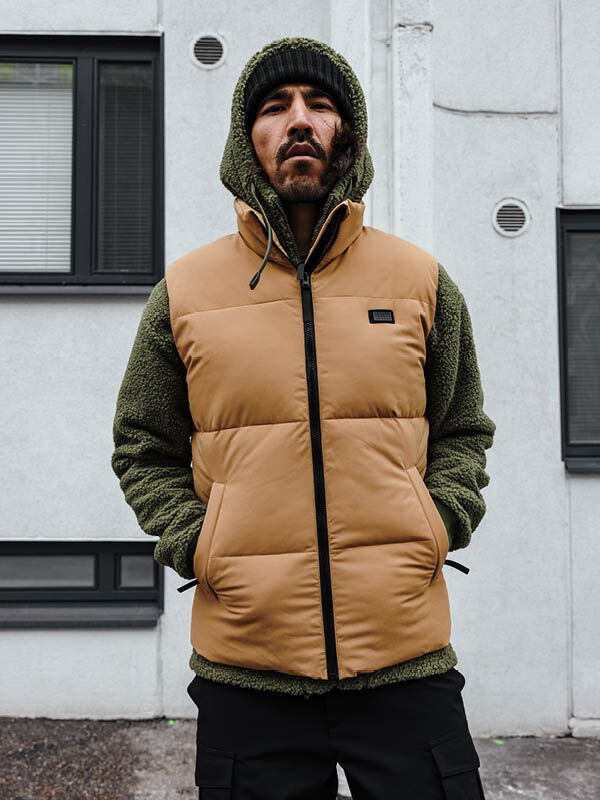 Mies seisoo ulkona Halti Penger Classic Puffer Liivi Miesten vihreä huppari päällä.