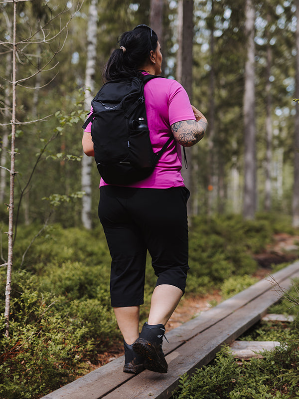 Nainen vaeltaa Halti Drive X-stretch Caprit Naisten Plussalla nauttien joustavasta kangasta ja UPF 50+ aurinkosuojasta.