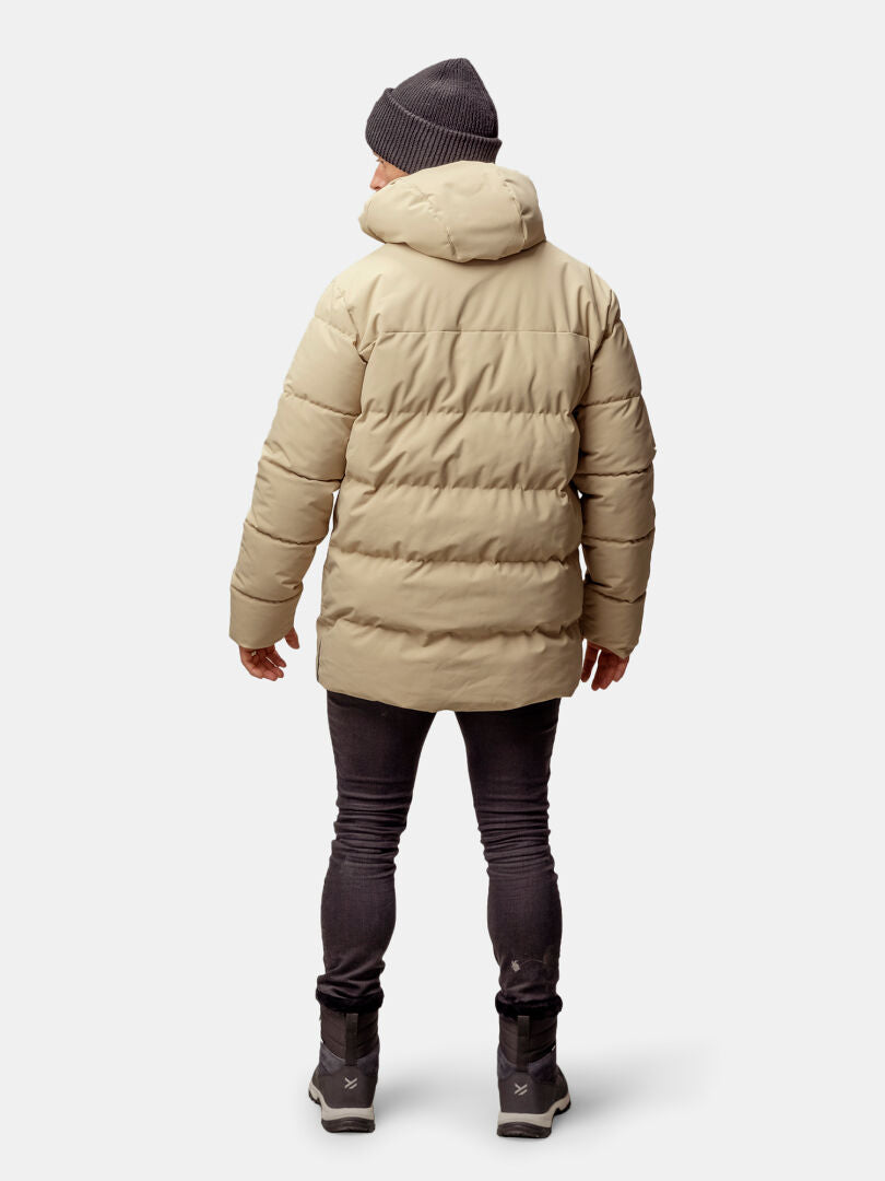 Henkilö, jolla on beige Halti Sammal Topattu Parkatakki -mies, harmaa pipo, tummat farkut ja saappaat, selkä kameraan päin.