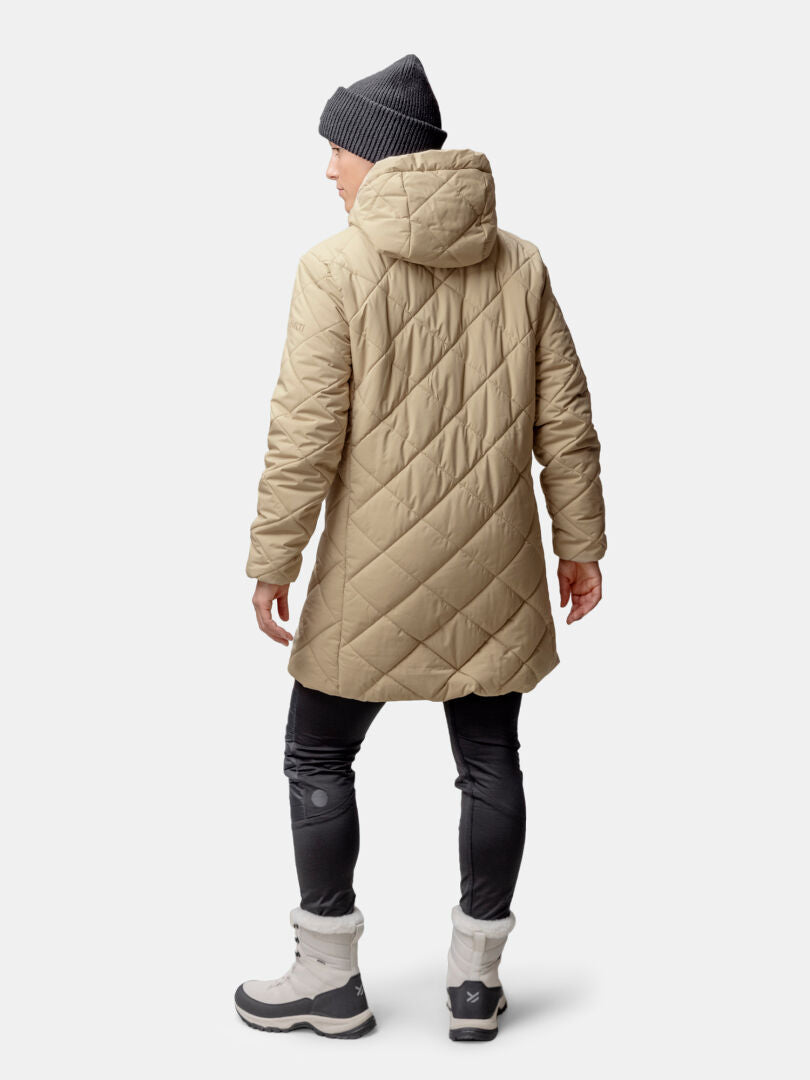 Henkilö, jolla on yllään Halti Haapa Tikkitakki Naisten, mustat leggingsit, harmaat saappaat ja harmaa pipo takaapäin kuvattuna.