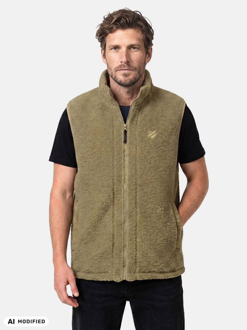 Mies, jolla on yllään Halti Lykky Fleece Liivi Unisex -liivi mustan t-paidan päällä, vaalea tausta, valmistettu kierrätetystä polyesteristä.