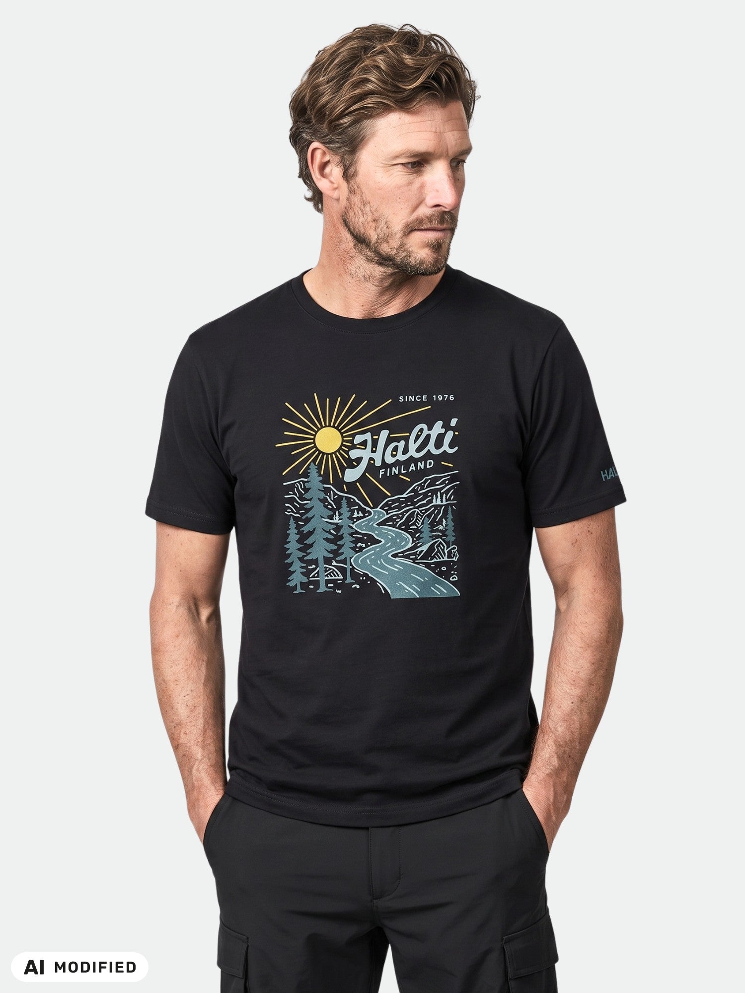 Mies, jolla on yllään musta Halti Vehka Unisex -T-paita, orgaanista puuvillaa, graafisia kuvioita, kädet taskussa.