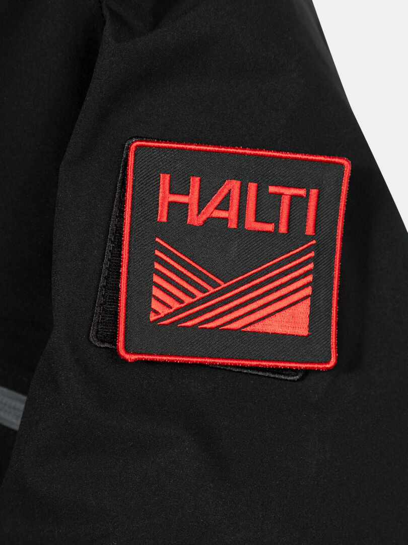 Lähikuva mustasta kangaslaastarista, jossa on punainen Halti-logo Halti 1976 Down Parka Unisex -mallissa.