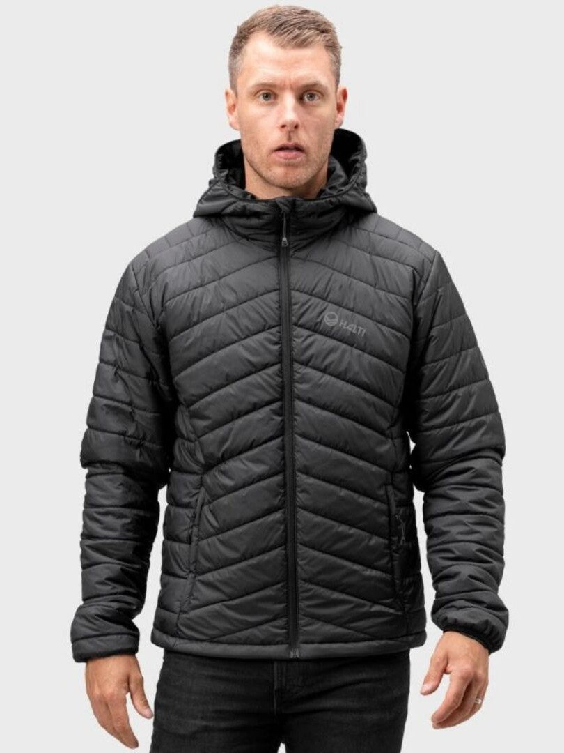 Miehellä on Halti Komu Kevytvanutakki Miesten (musta) vaaleanharmaalla pohjalla.