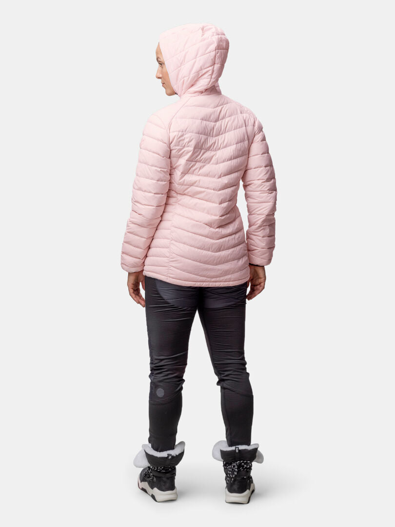Henkilö seisoo etäällä, yllään Halti Huippu Mid Untuvatakki Naisten, tummat housut ja talvisaappaat.