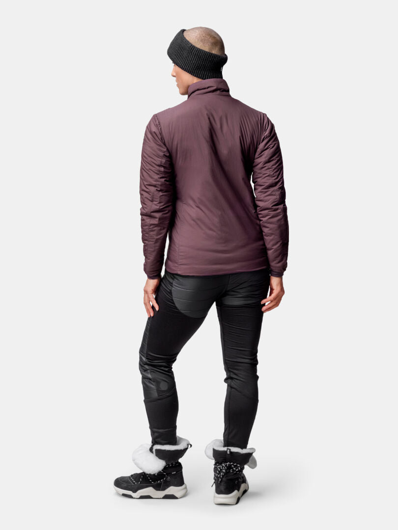 Henkilö kasvot menosuuntaan ruskeankeltaisessa Halti Haave Primaloft Takki Naisten, mustissa housuissa ja saappaissa, valmiina ulkoiluun.