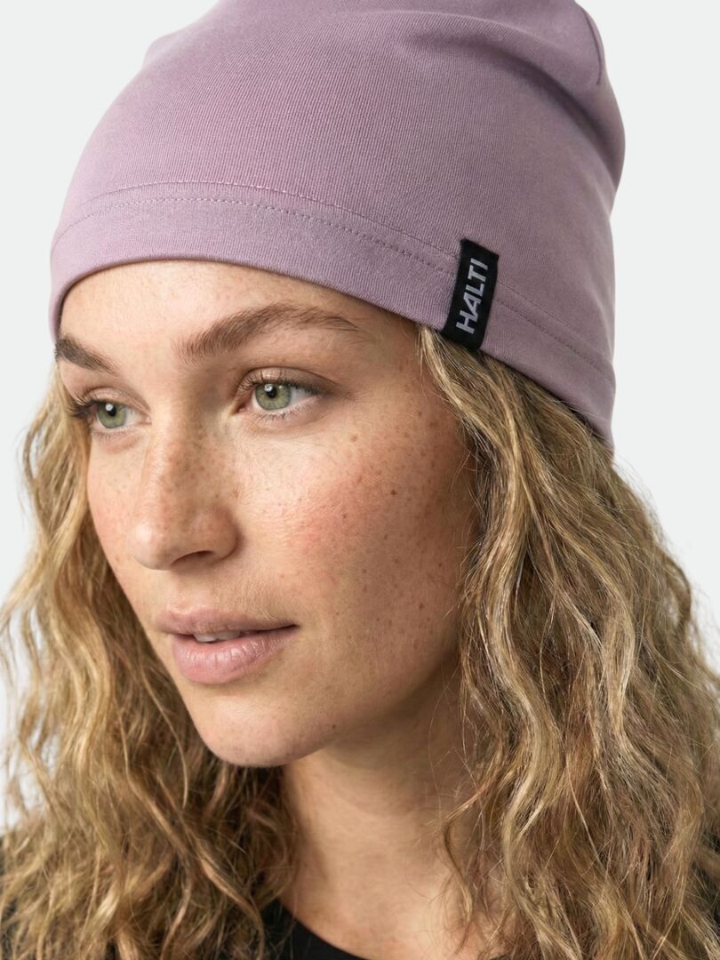 Kihara vaaleahiuksinen henkilö käyttää vaaleanviolettia Halti Loiva Pipoa ja katsoo hieman sivulle.